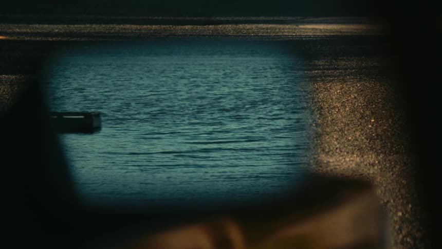 A calm sea reflected in a rearview mirror