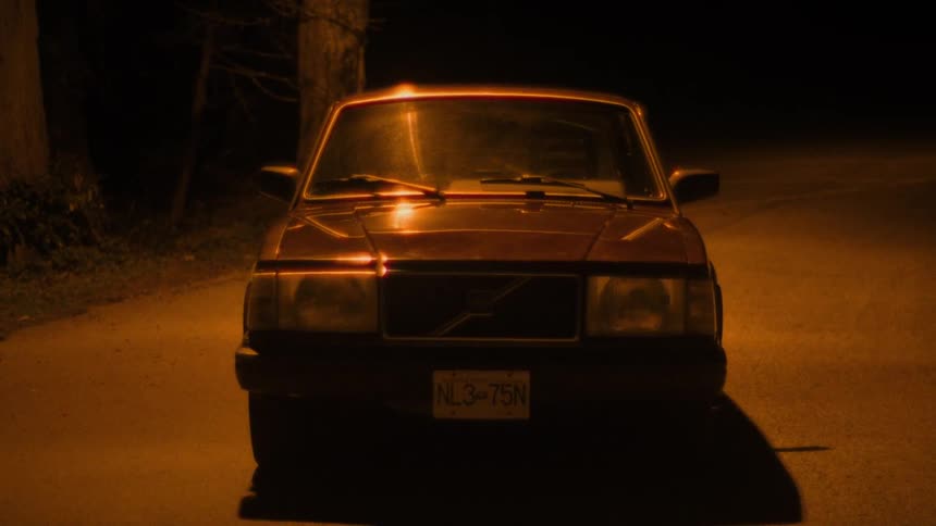 Streetlight reflects from windshield of car parked in the road at night