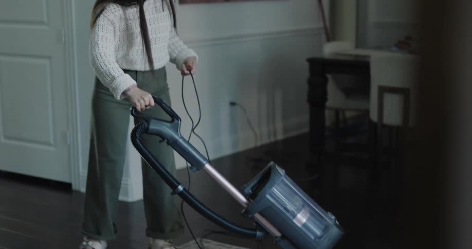 A young woman vacuuming a living room carpet