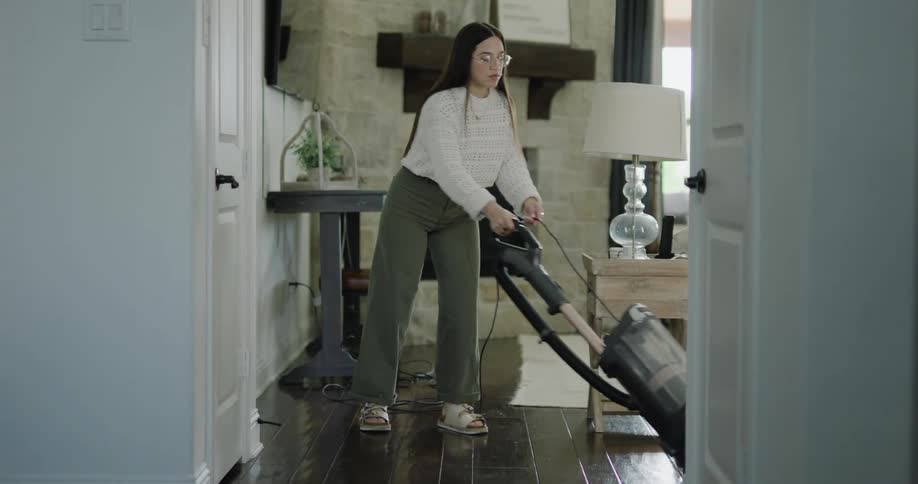A young woman vacuuming a living room