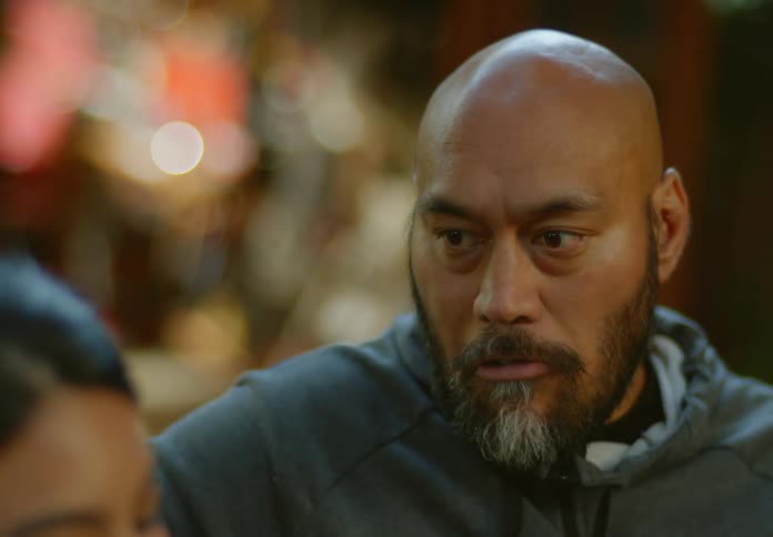 A man is eating something as he listens to a woman