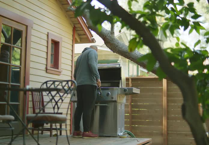 A man opens and cleans his grill