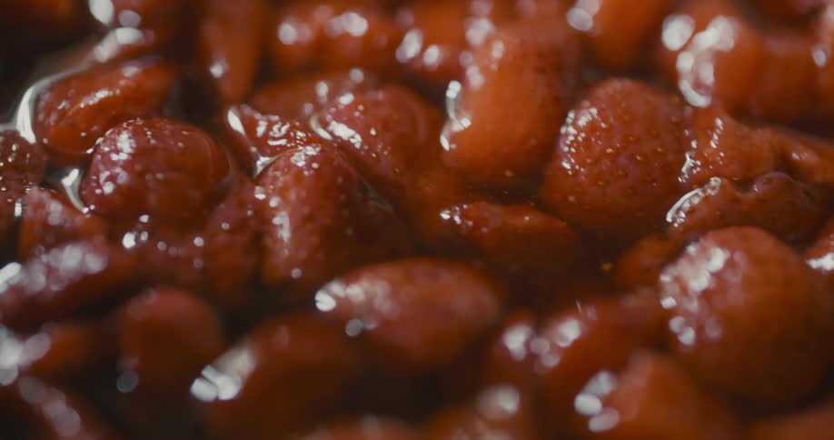 Strawberries are being mixed together with a spoon