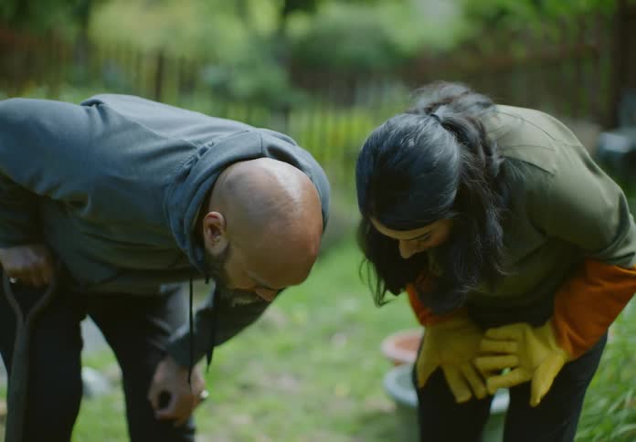 A man and woman talk as they are gardening