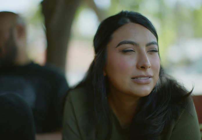 Woman smiles while sitting outdoors and talking to a man