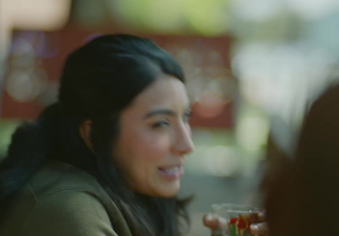 A woman is drinking something from a flowered glass and she is laughing while i talk to someone