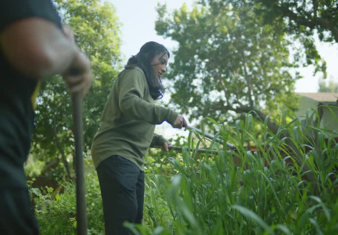 Man and woman perform yard work at home during the day
