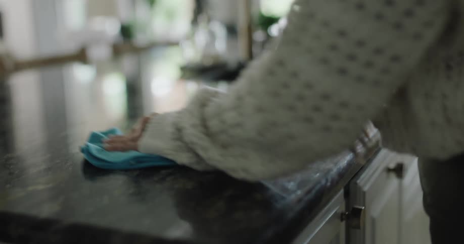 A woman is cleaning the counter with a rag