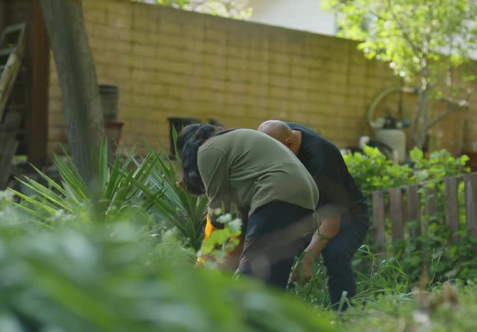 A man and woman are gardening in their yard