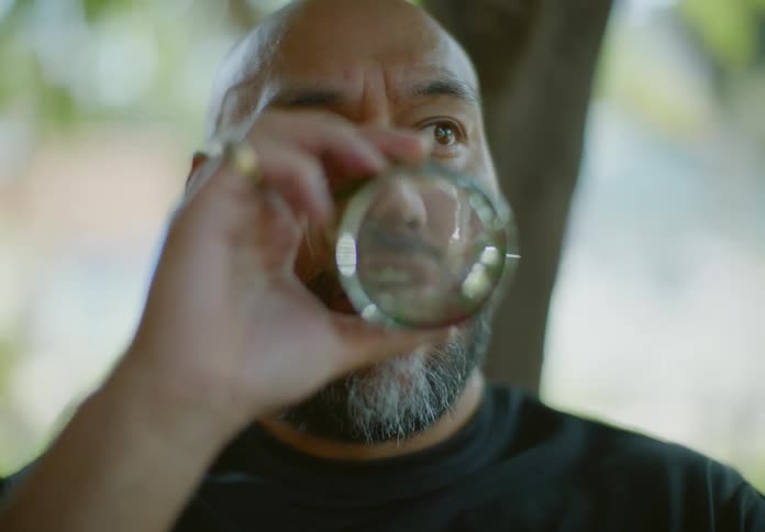 Portrait of a bearded man outdoors drinking a glass of water