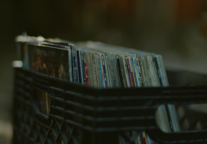 A black crate full of old vintage vinyl record albums sits in a storage room.