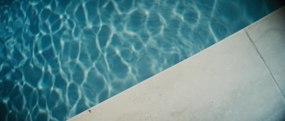 The edge of a swimming pool with clear water on a bright day