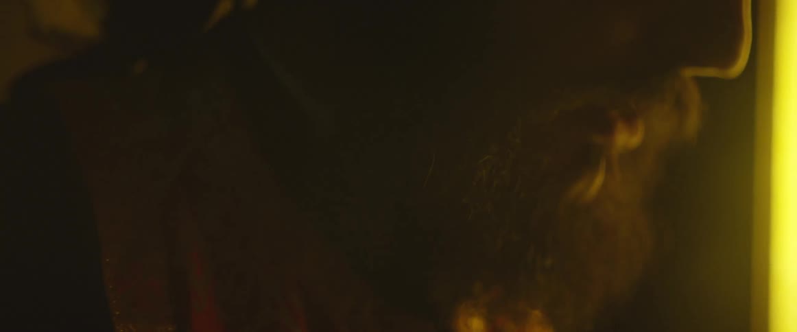 Close-up of bearded man moving his lips in a dark setting