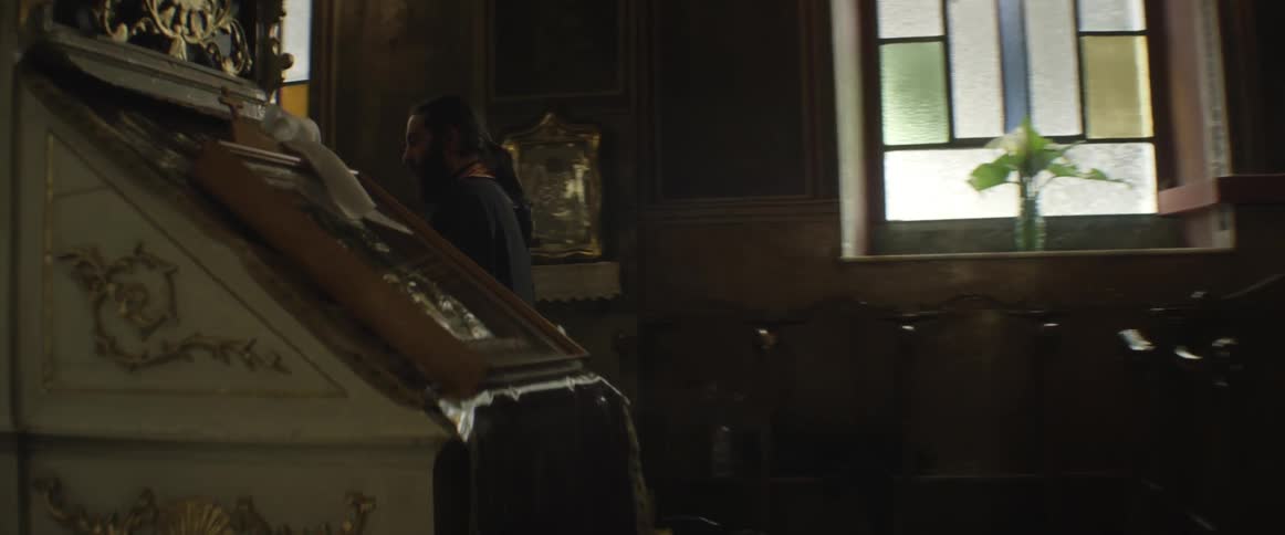Man wearing a robe walking inside a cluttered church