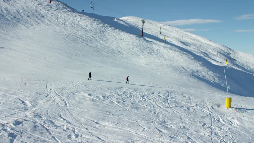 A couple of skiers leisurely skiing down a mountain slope