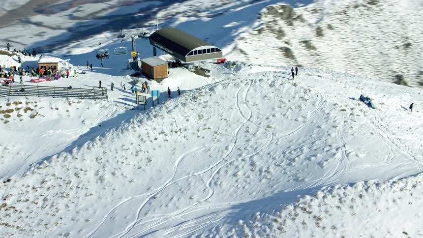 Snowcovered mountain landscape with several ski slopes and a cable car station at the top