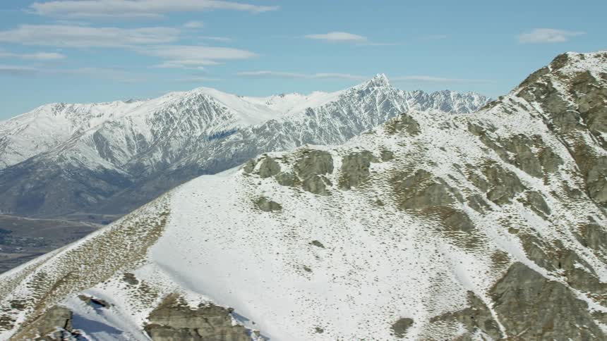 A snow covered mountain range with a valley below it is shown in aerial view