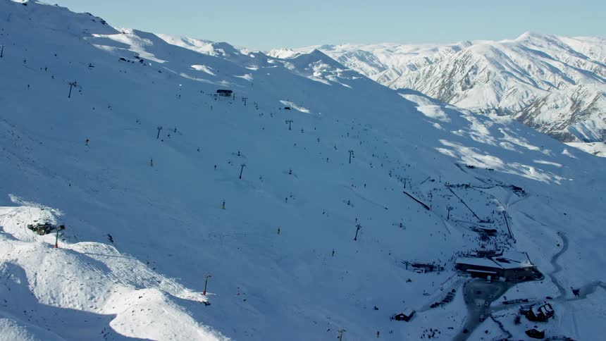 Coronet Peak ski field with lifts and buildings at the base of the snow covered mountains