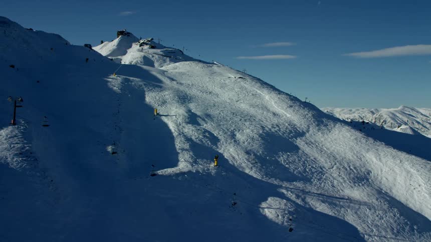 A snowcovered mountain slope with ski lifts and skiers