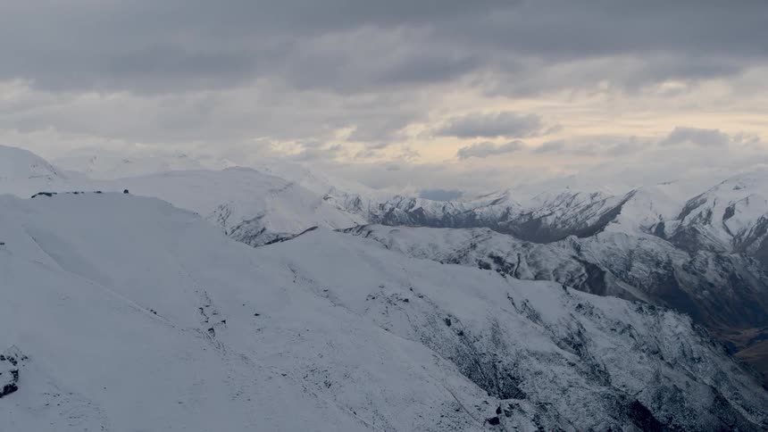 The mountain range is covered with snow on an overcast day