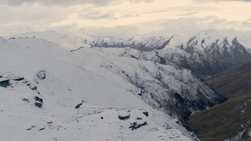 Aerial view of a mountainous landscape covered with snow under a cloudy sky