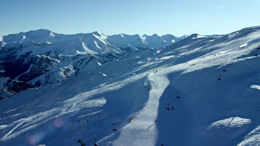 A snow covered mountain slope with ski lifts and skiers