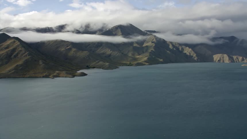 Profile tracking across a large lake with mountain range and interesting clouds
