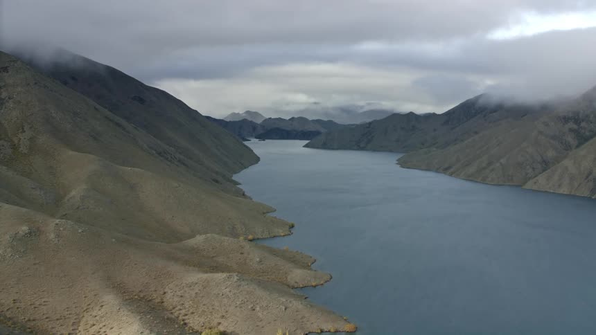A large lake runs through the mountains under an interesting sky