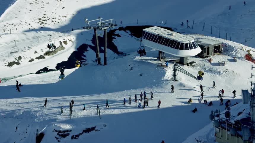 The ski lift carries skiers and snowboarders up the snowcapped mountain slope
