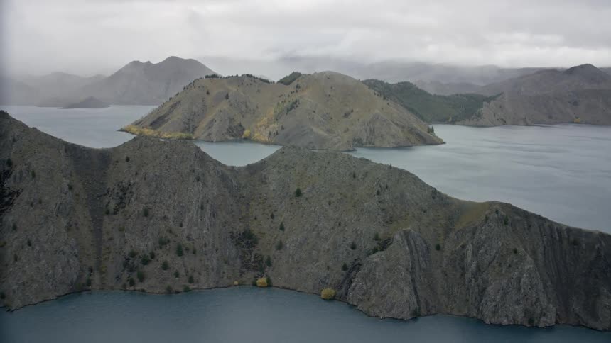 Flying over dramatic islands covered with hills rising out of the moody lake