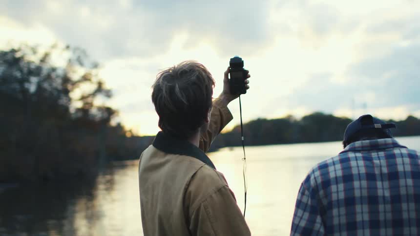A photographer uses a light meter with his friend