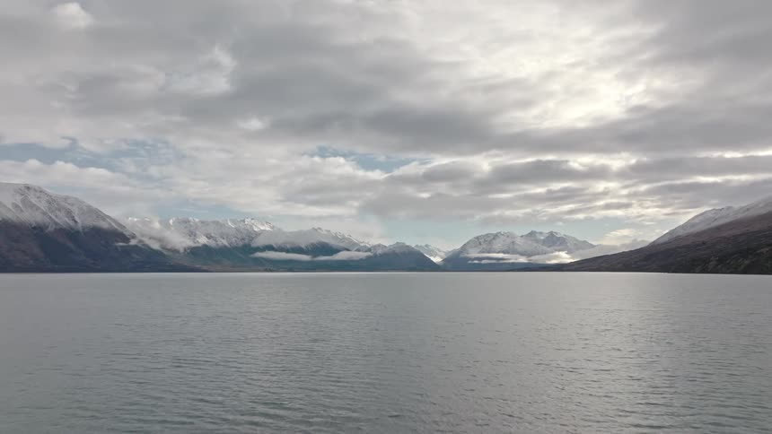 Vast body of water with a mountain range in the background under a cloudy sky