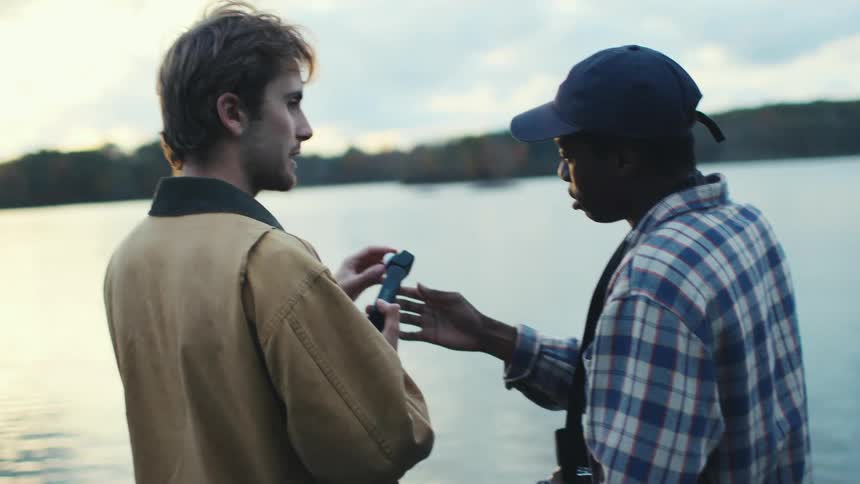 A young man shows his friend how to use a light meter