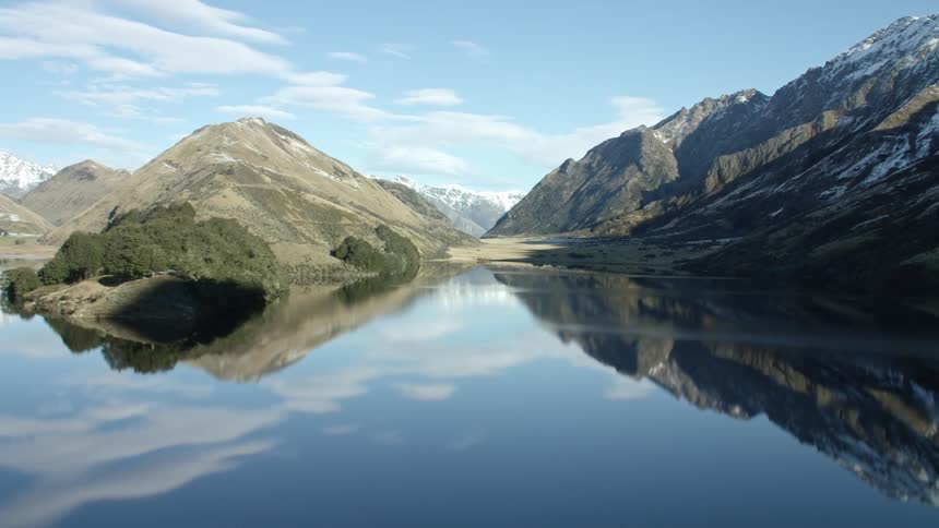 The sky is reflecting on the lake water with dramatic winter mountains