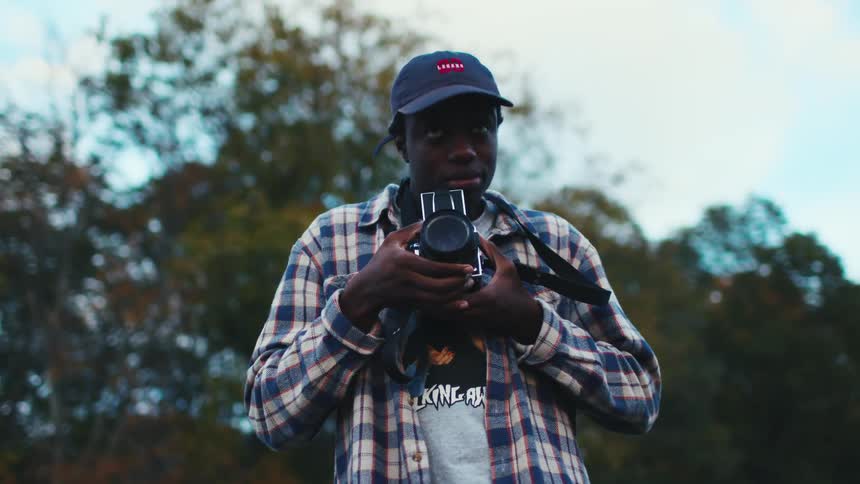 A young photographer frames up a shot on his vintage camera