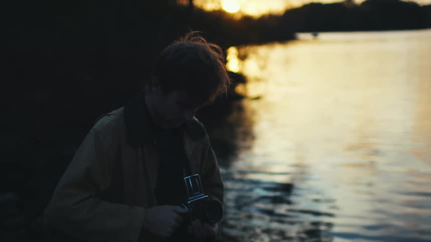 A man takes photographs by a lake
