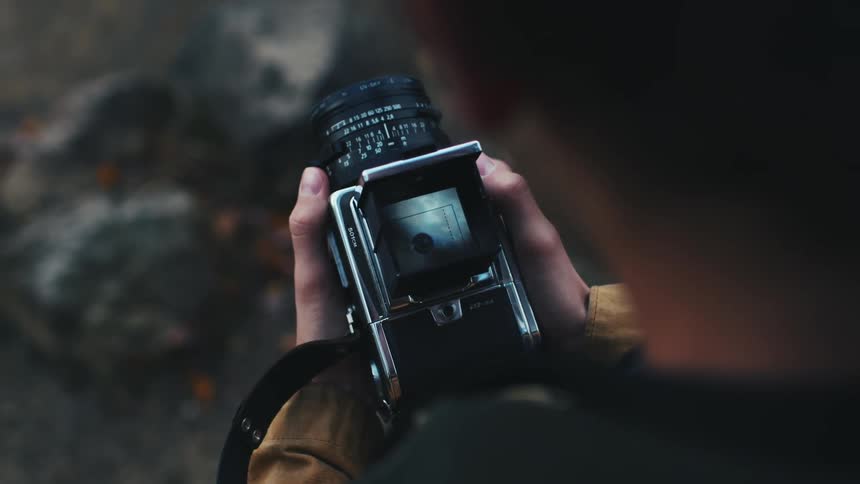 A man takes a photograph of his friend on the shore