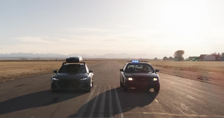 Gray car threatens to hit the police car next to it which ends up swerving off the road
