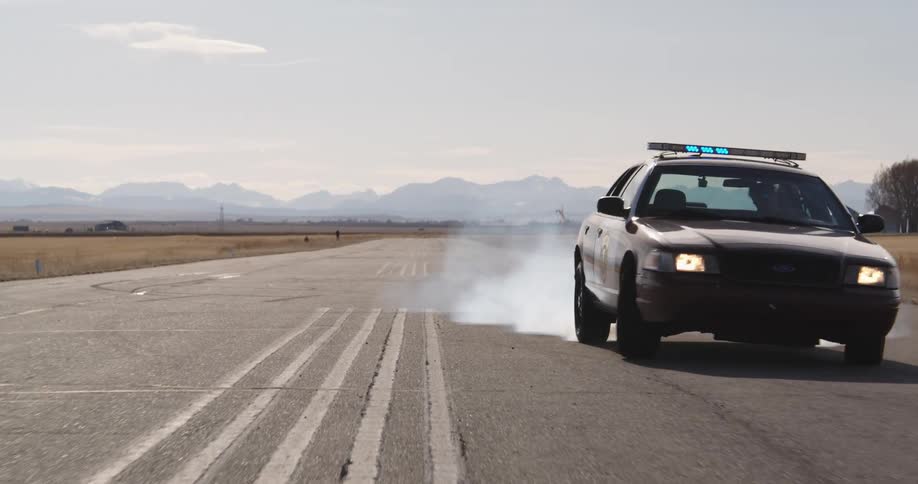 Police car at high speed performing a maneuver with smoke coming from the tires