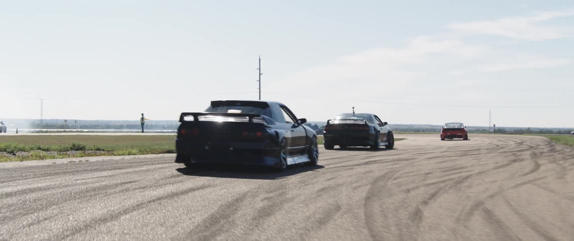 Sports cars on a race track skidding and leaving a trail of tire smoke