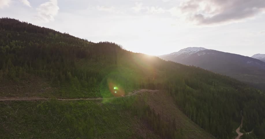 Aerial view of the winding dirt path of a mountain bike trail snakes through a lush green forest