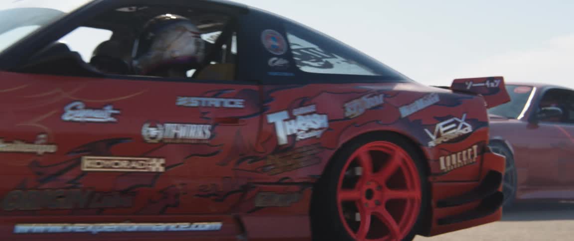Two race cars drive by the shore
