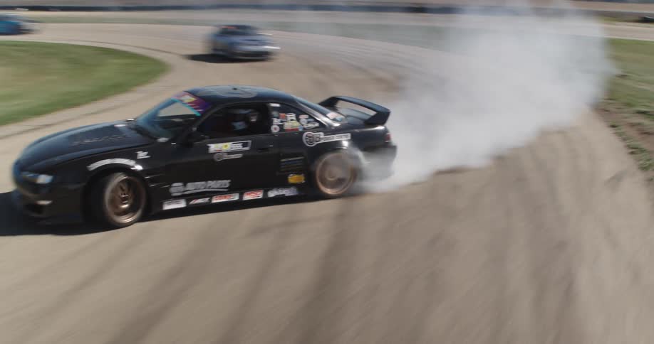 A racing car drifting around a curve on a track and making smoke from its tires