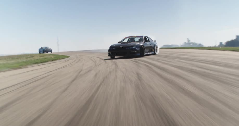 Moving black sports car skidding on a track with smoke visible from the tires