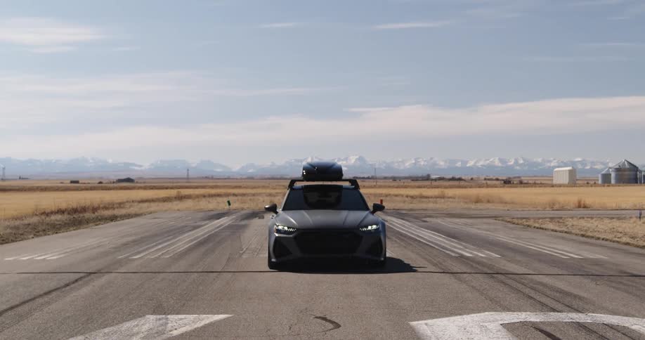 Car with a luggage box on the roof parked in the middle of an airport runway