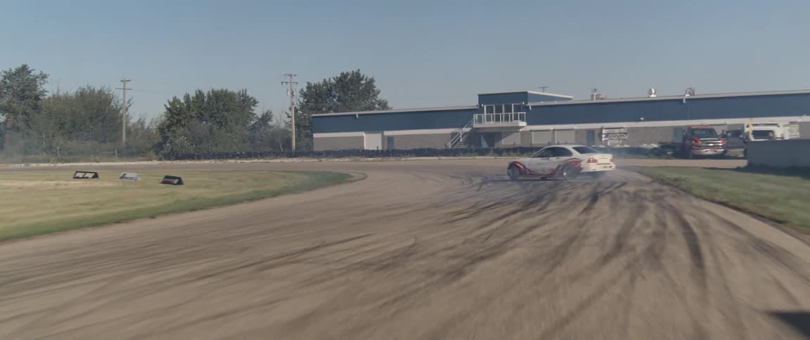 A white race car drifting on a track leaving behind a trail of smoke