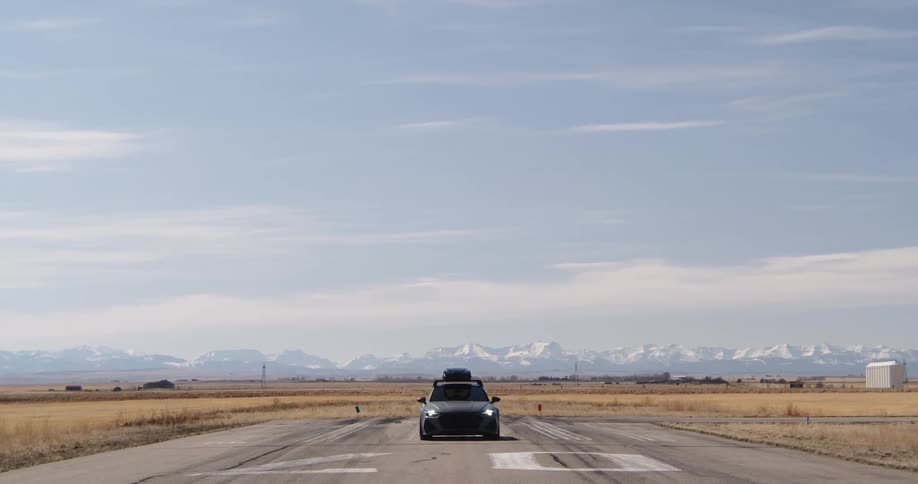 Black sports car stopped on a wide aviation road