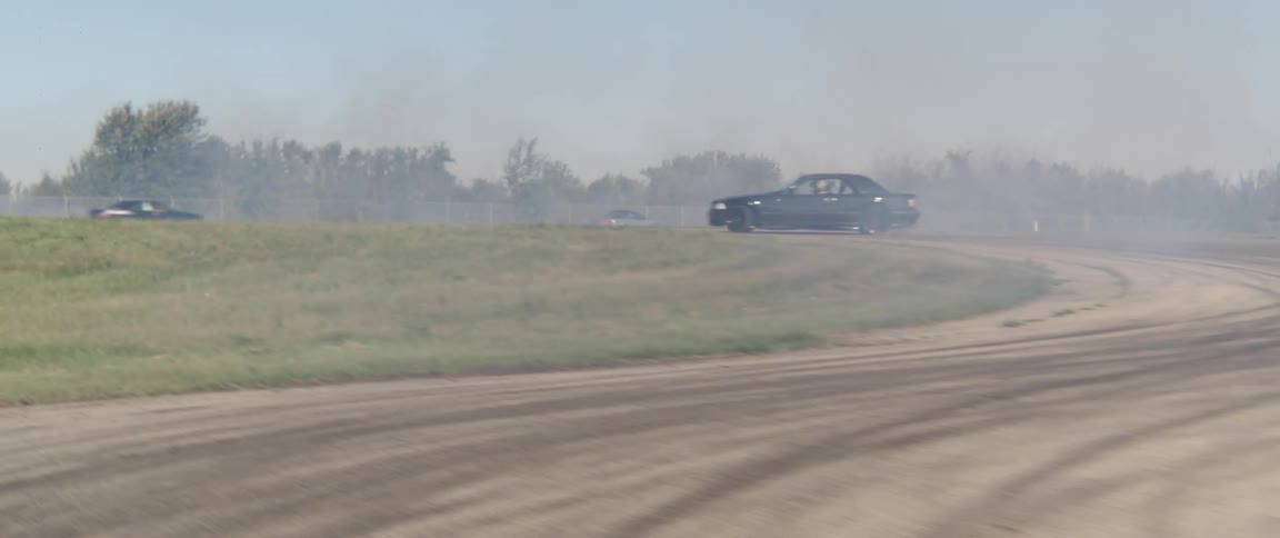 Sports cars in motion skidding on a track with smoke visible