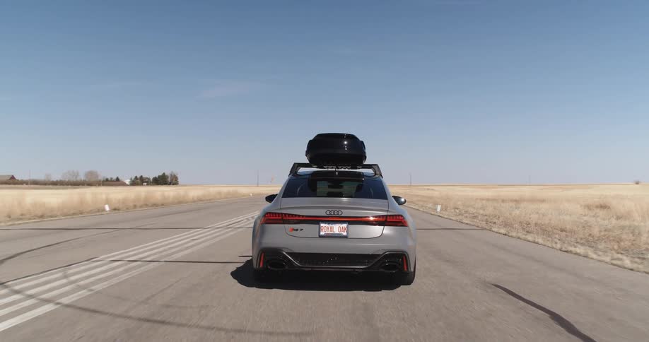 A car with a roof box driving on the tarmac of an airfield