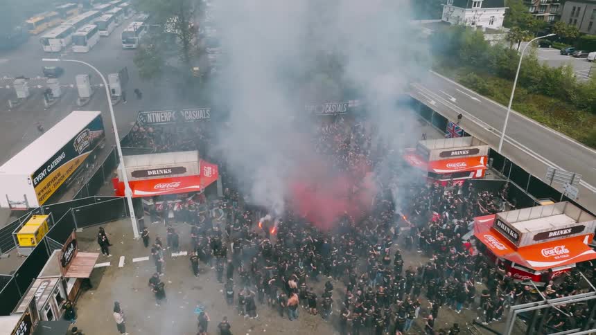 Colored smoke floats over large crowd at an outdoor event